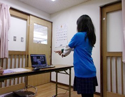 写真：パソコン画面に向かって、手を前に伸ばしポーズをとる少女
