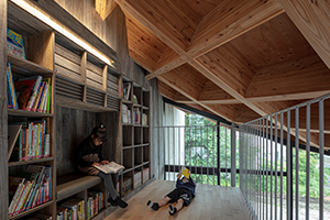 写真：壁一面の本棚と、好きな姿勢で読む二人の子ども