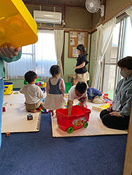 3枚の写真：室内のワンルームで、おもちゃで遊ぶ3、4人の乳幼児と、大人たち