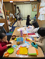 写真：同じ座卓で勉強する子どもと、工作する二人の子ども
