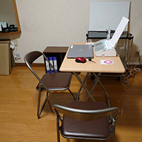写真：ファックスやパソコンが置かれた小さな机と小さなホワイトボードがある部屋